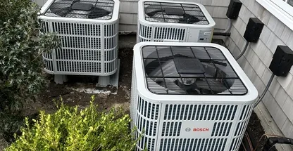 Residential heat pump condenser unit alongside Long Island home exterior